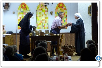 Novizin Gloria soll das Holz wieder auf den Stapel zurückbringen.